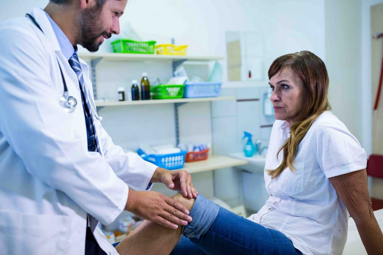 Male doctor examining patients knee London’s Best Rheumatology Clinic